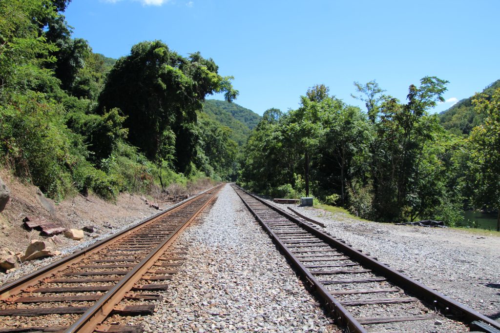 Two railroad tracks running side by side through green mountains, a reminder that when we fall off track, we don’t have to get back on alone.